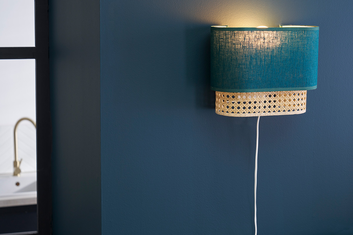 Applique murale bleu canard et rotin, vue de ct, sur mur bleu.