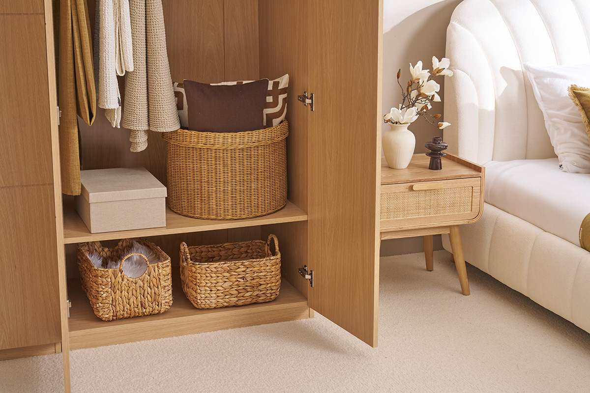 Armoire ouverte avec tagres, paniers en osier et vtements suspendus, prs d'un lit et table de chevet.