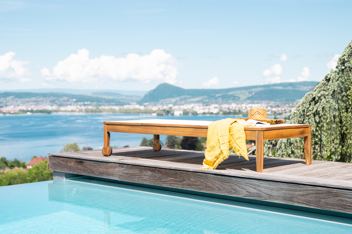 Bains de soleil NAVEEN en bois massif pr�s d'une piscine, avec une serviette jaune et un chapeau de paille.