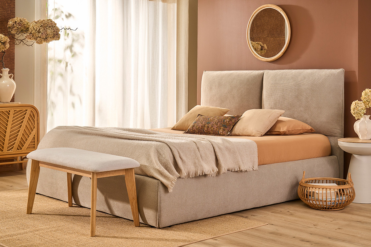 Banc scandinave beige en face du lit dans une chambre cosy.