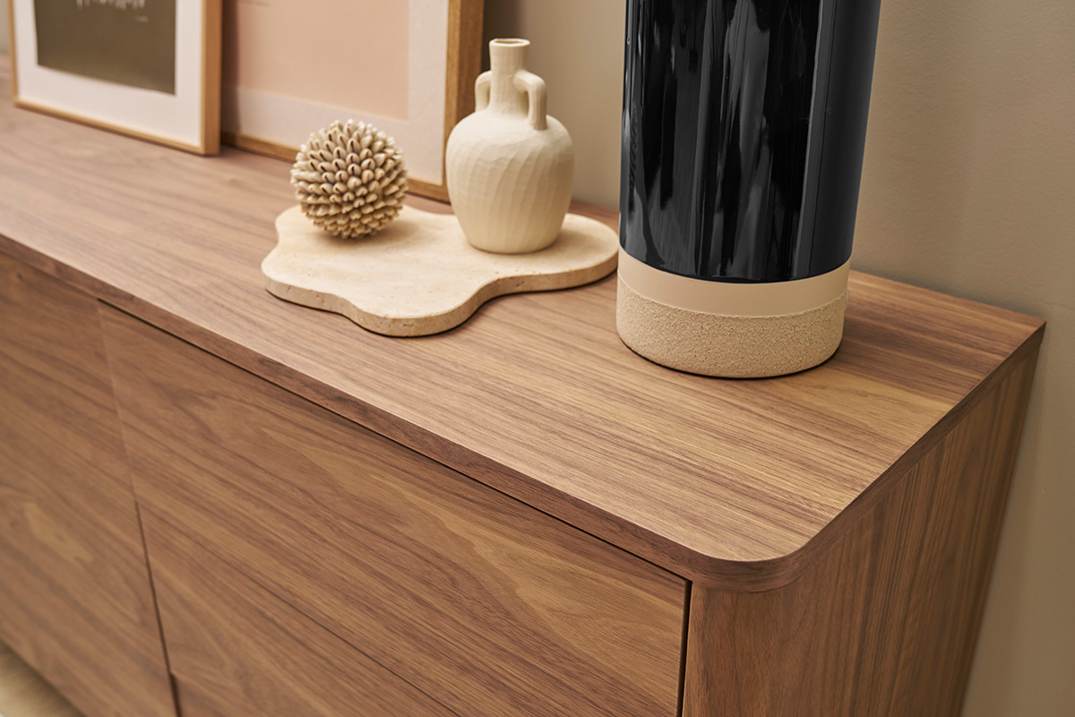 Buffet en bois fonc noyer avec objets dco sur le dessus, vue en angle.