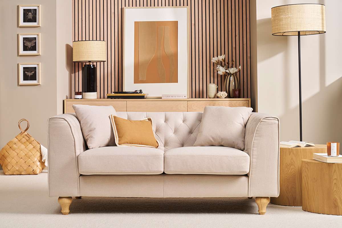 Canap 2 places capitonn beige avec coussins, vue de face.