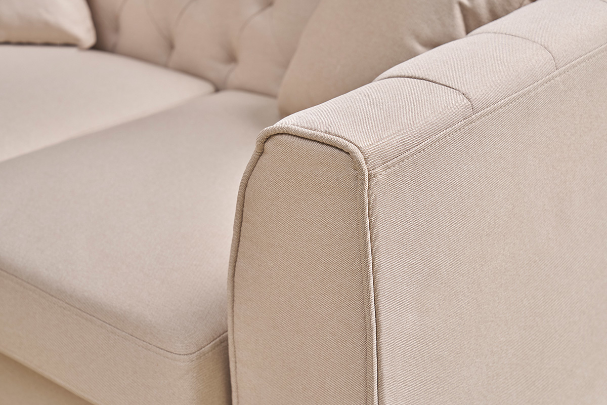 Gros plan sur accoudoir du canap 2 places MONTAIGNE en tissu beige avec capitonnage.