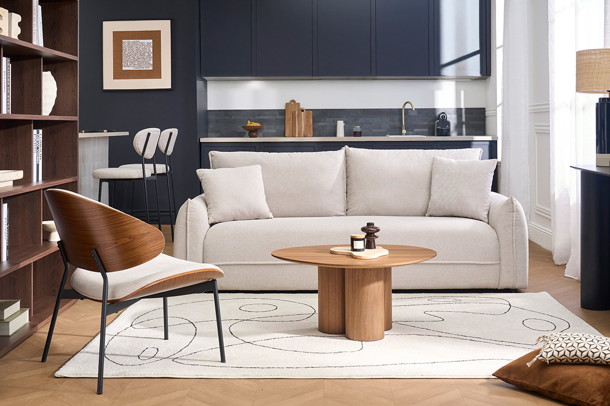 Canap� 3 places en tissu beige dans un salon moderne avec table basse en bois, vue de face.