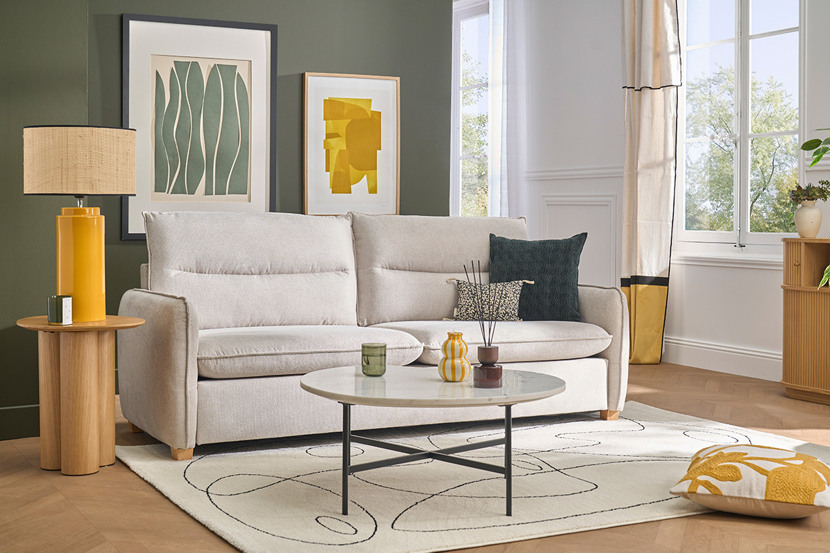 Canap� 3 places RENZO en tissu effet velours beige, vue de 3/4 avec d�coration int�rieure.