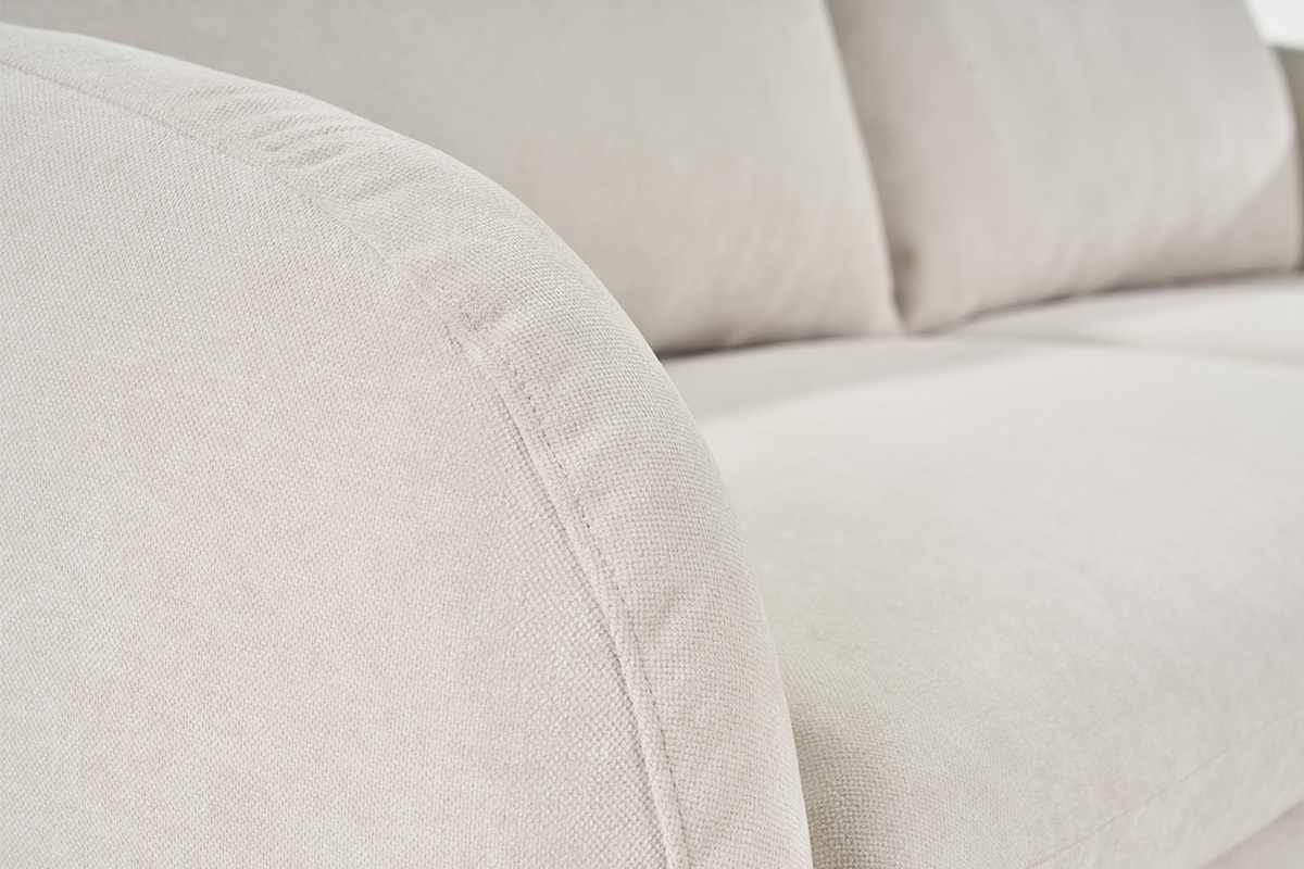 Gros plan sur le canap� en tissu effet velours beige, accoudoir arrondi.