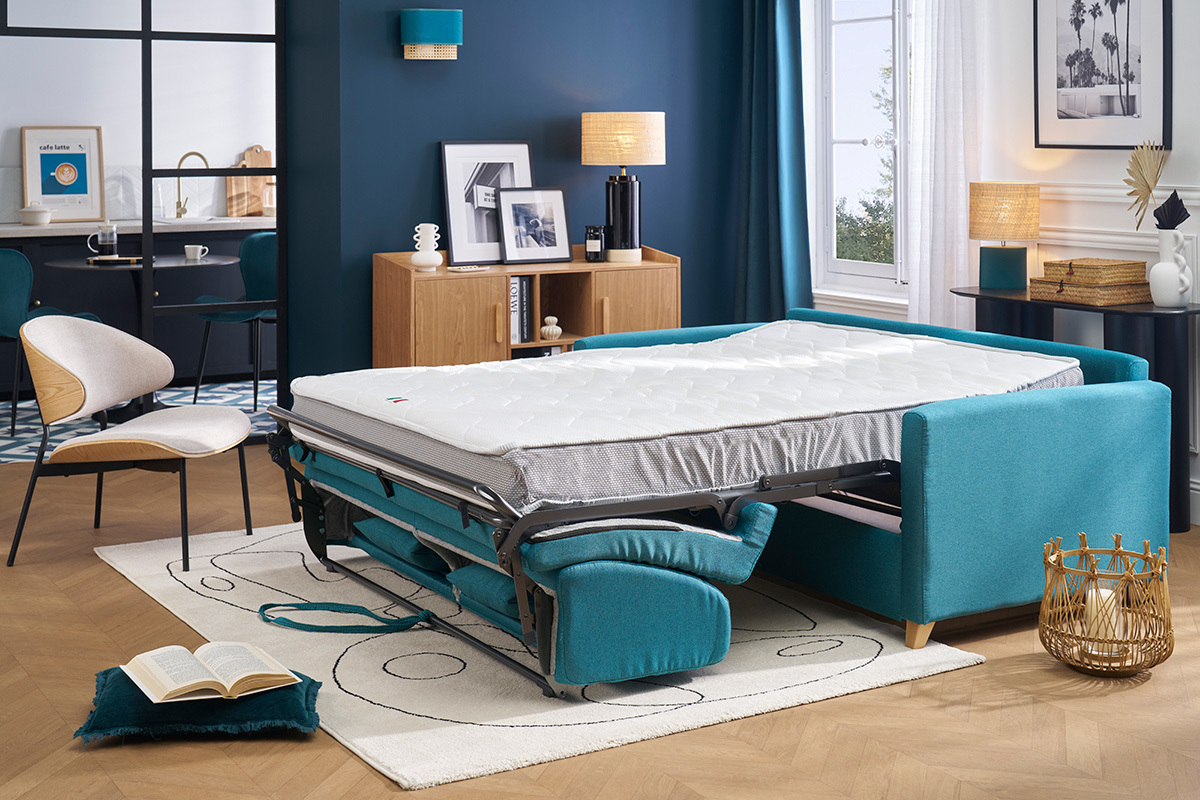 Canap convertible bleu canard avec matelas dpli dans un salon moderne.