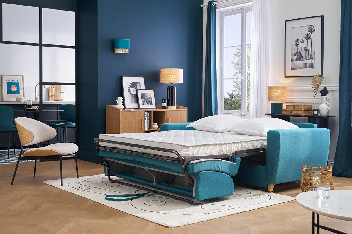 Canap convertible bleu canard ouvert avec matelas dans un salon moderne.