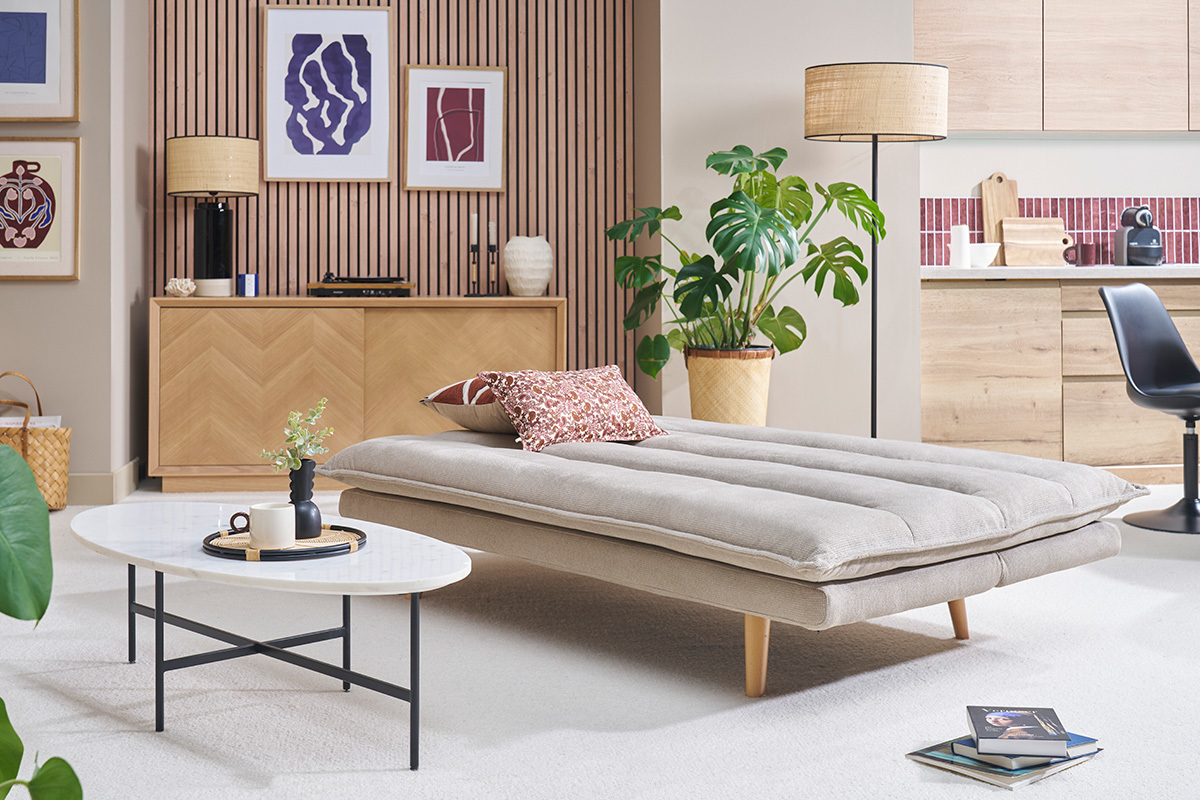 Canap convertible BINGO beige en position lit avec pieds en bois clair, table basse blanche devant.