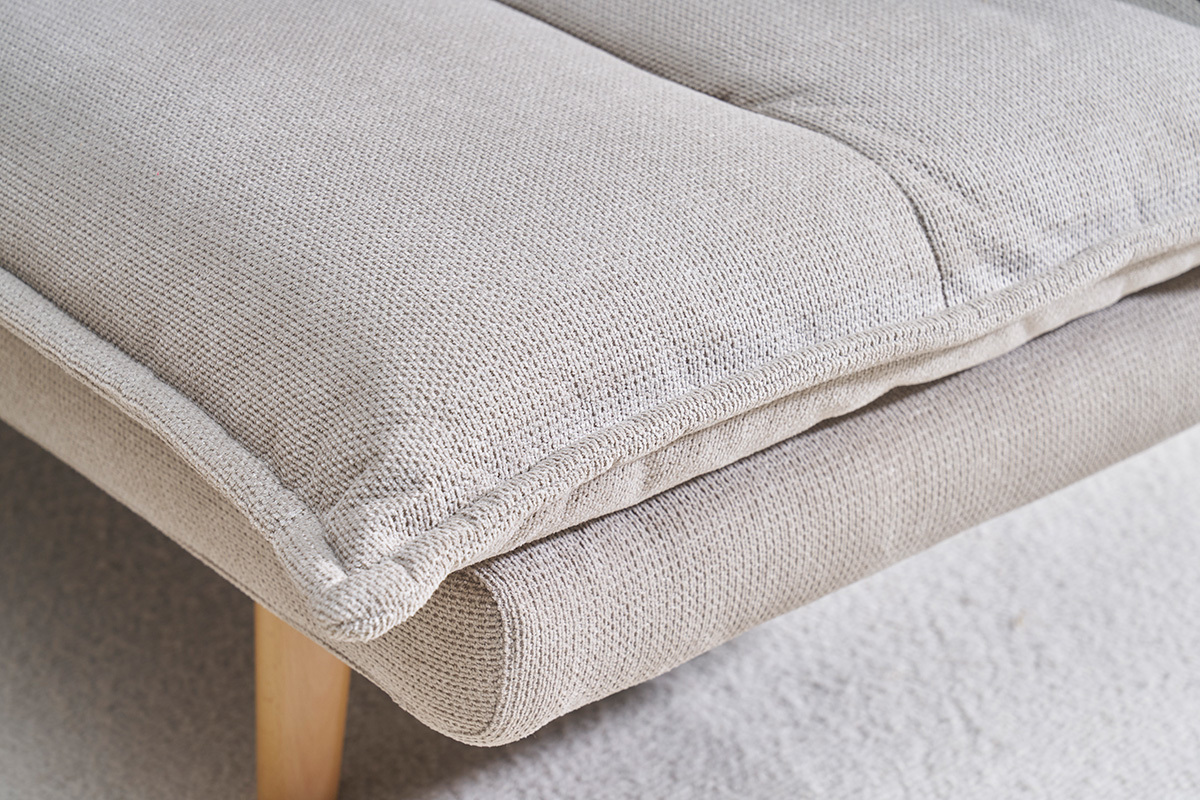Gros plan d'un canap convertible en tissu chenille beige avec pieds en bois clair.