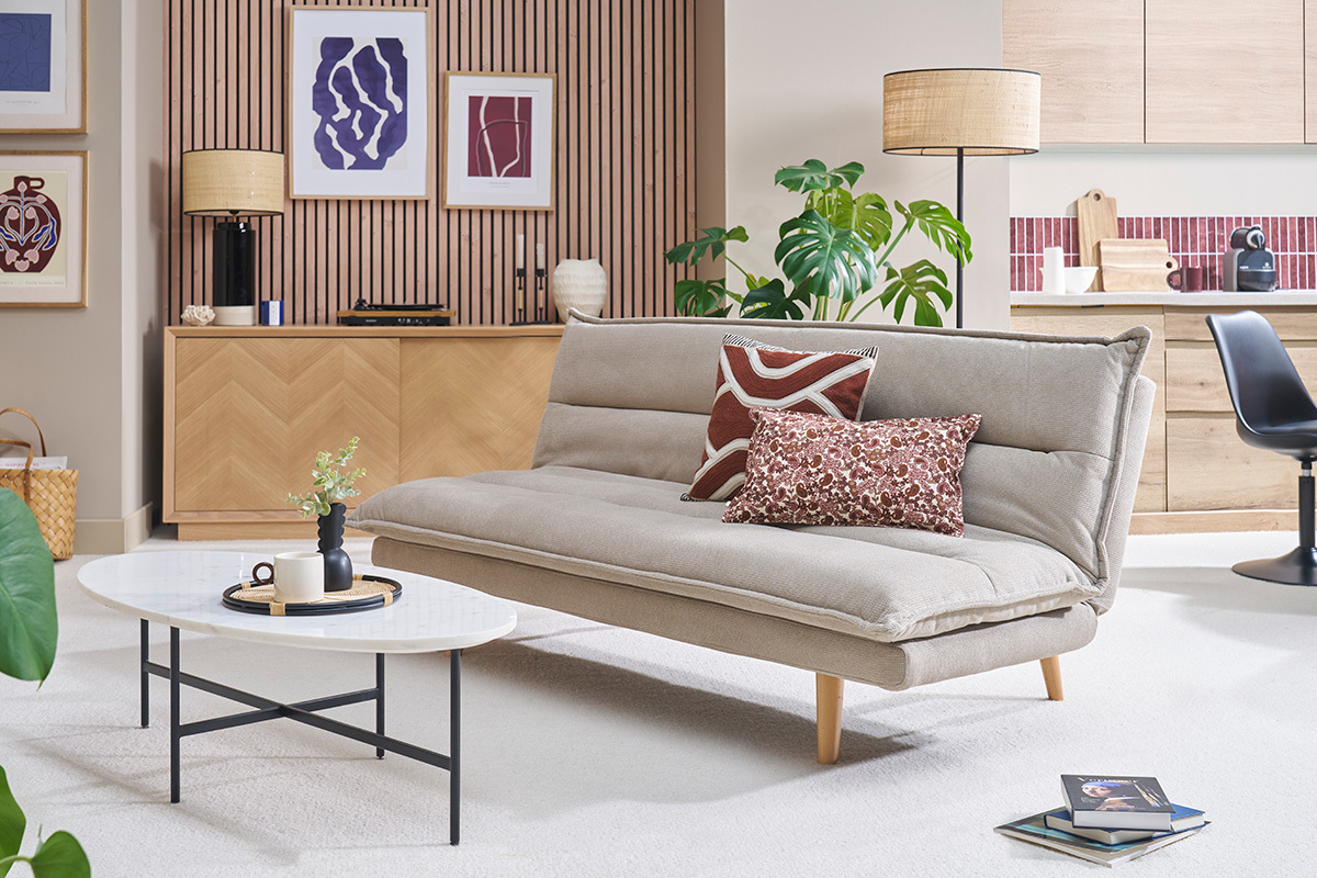 Canap convertible beige en tissu chenille avec pieds en bois, vue de ct dans un salon moderne.