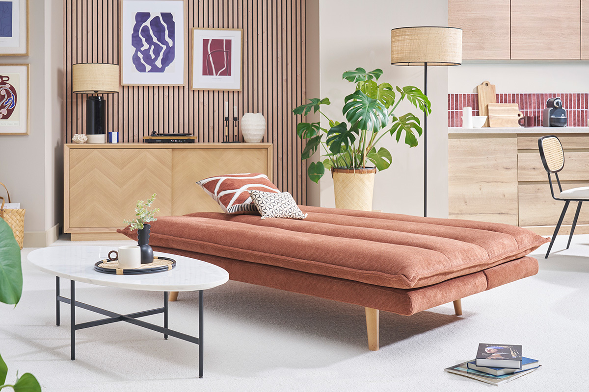 Canap convertible en tissu terre brle dpli, pieds en bois, dans un salon moderne.
