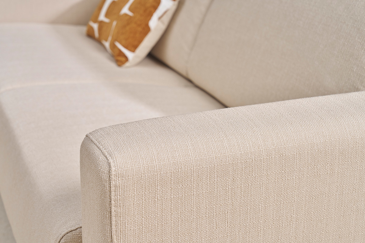 Accoudoir d'un canap beige en tissu avec coussin dcoratif. Vue en gros plan.