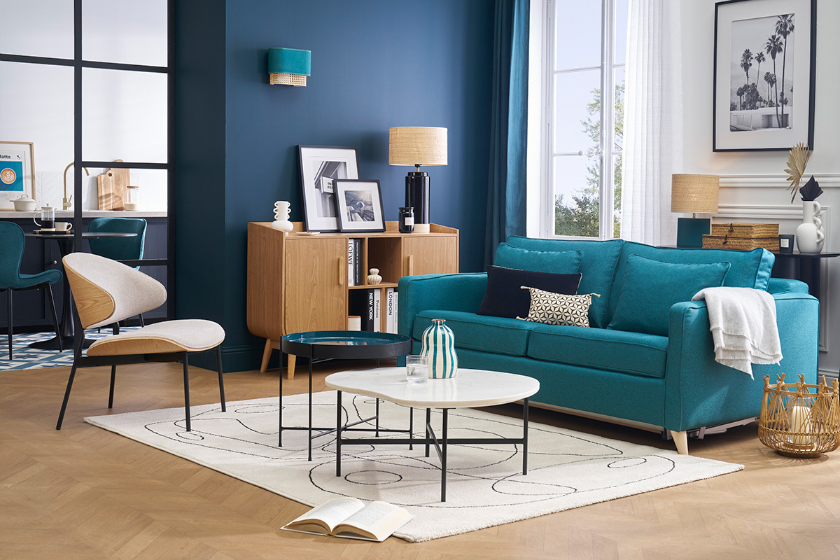 Canap convertible bleu canard 3 places avec tables basses modernes en salon.