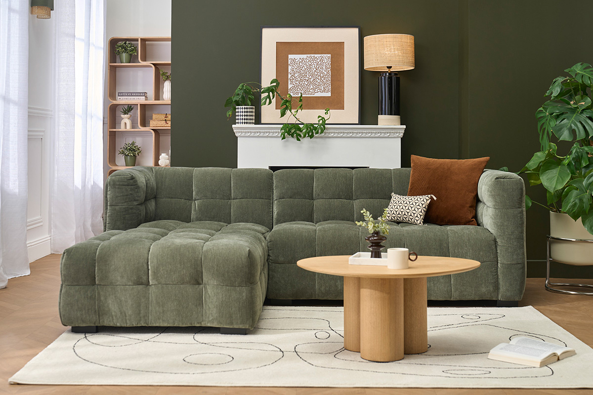 Canap� d'angle gauche en velours vert kaki, vue de face avec une table basse et des accessoires d�co.