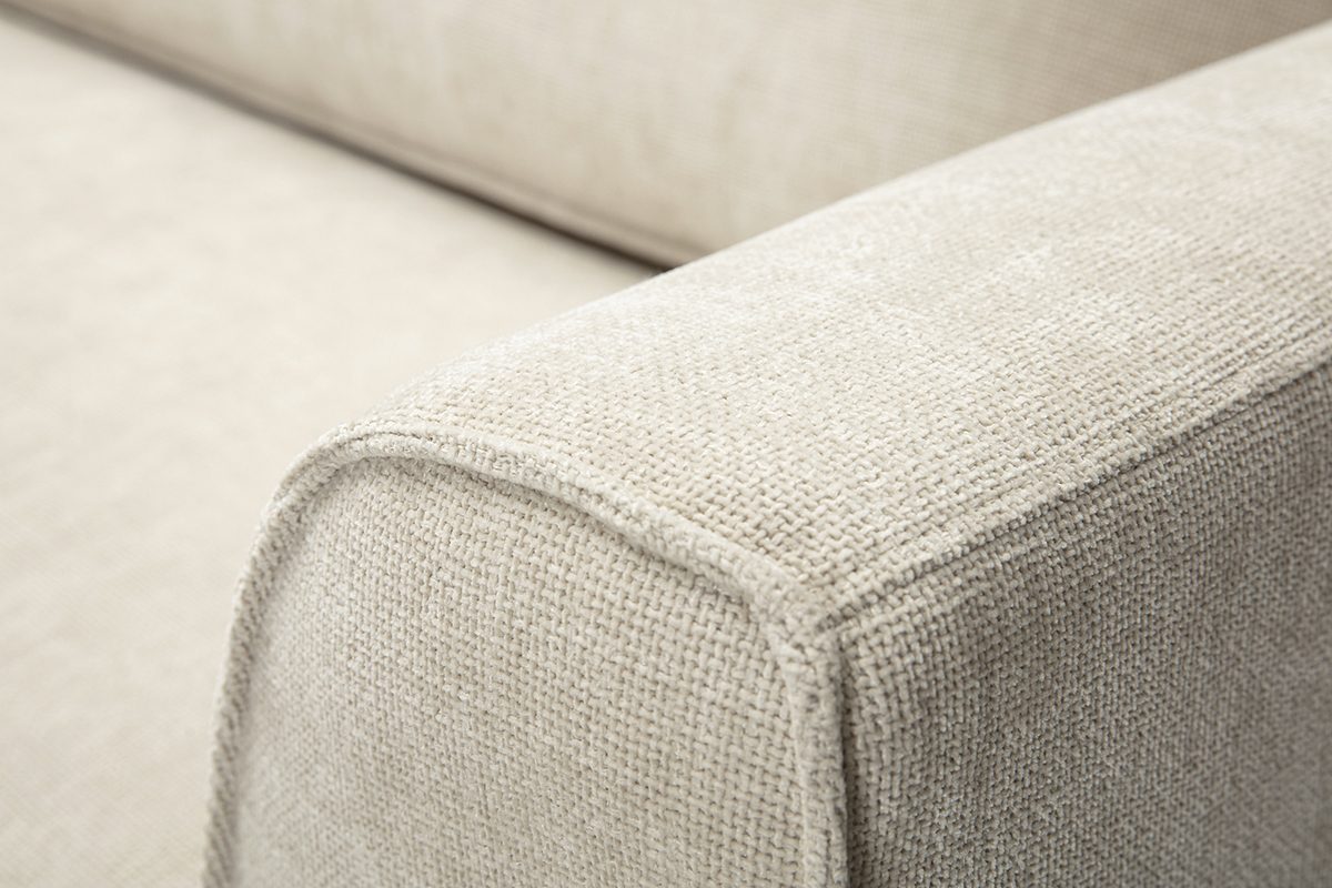 Gros plan sur l'accoudoir d'un canap� en tissu effet velours textur� beige.