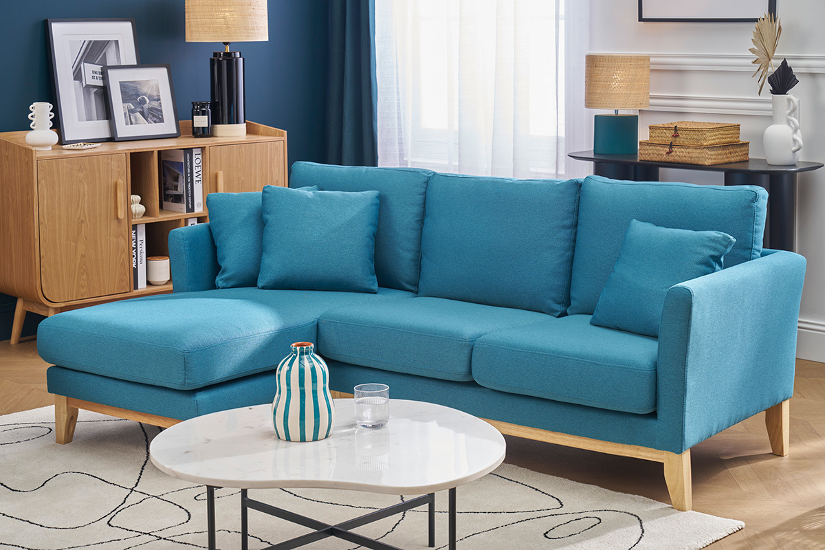Canap d'angle gauche bleu canard et bois clair, dans un salon avec table basse et buffet en bois.