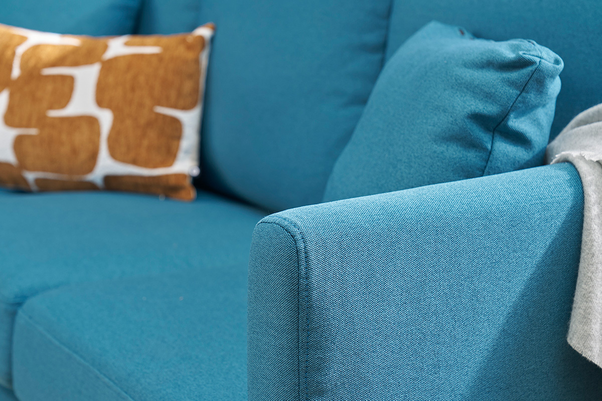 Gros plan sur un canap d'angle bleu canard avec coussins.
