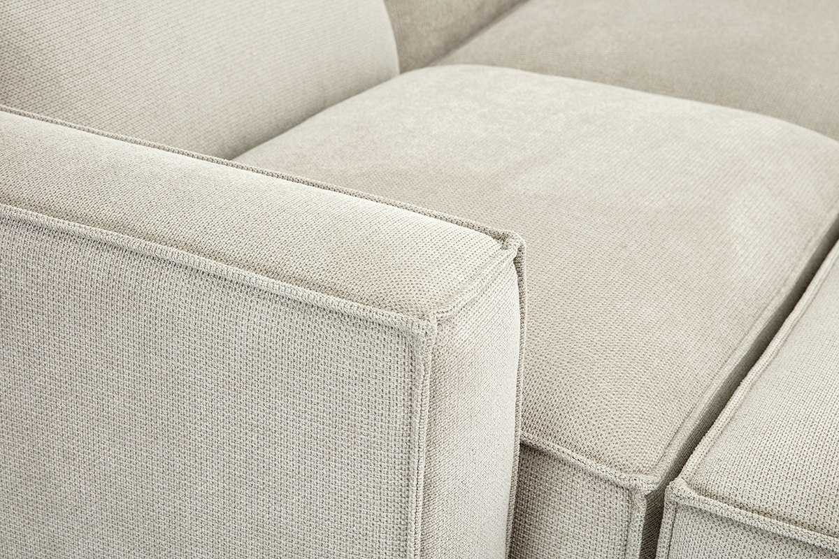 Gros plan sur un canap d'angle modulable en tissu effet velours textur beige.