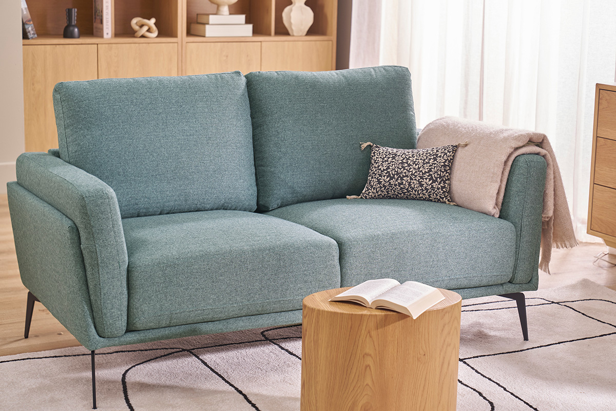 Canap� 2 places vert de gris avec pieds noirs, vue de 3/4 dans un salon.