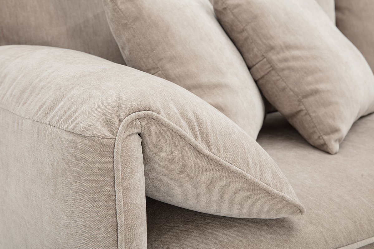 Gros plan sur accoudoir et coussins du canap� TANTOR en tissu effet velours taupe.