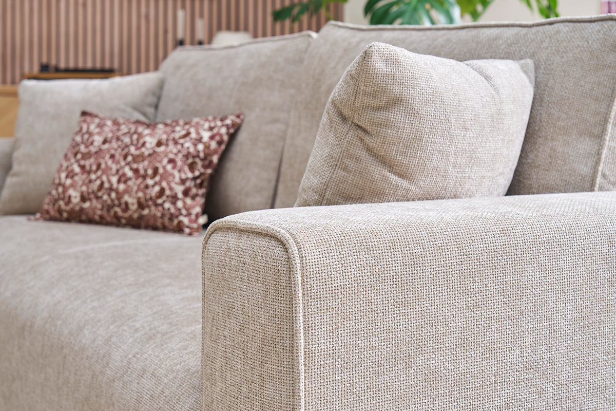 Canap beige effet velours textur, accoudoir et coussins visibles, vue de ct.