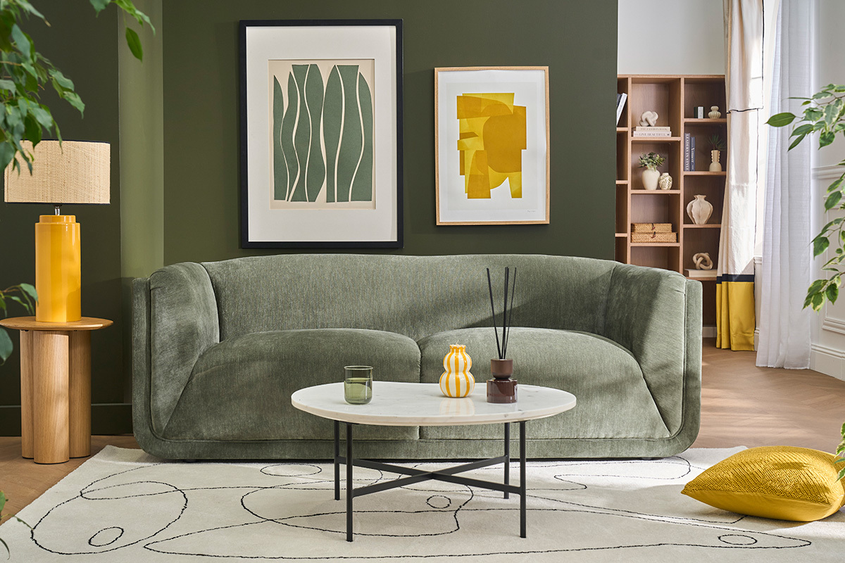 Canap� 3 places en tissu velours vert kaki, vue de face, avec table basse et d�corations.