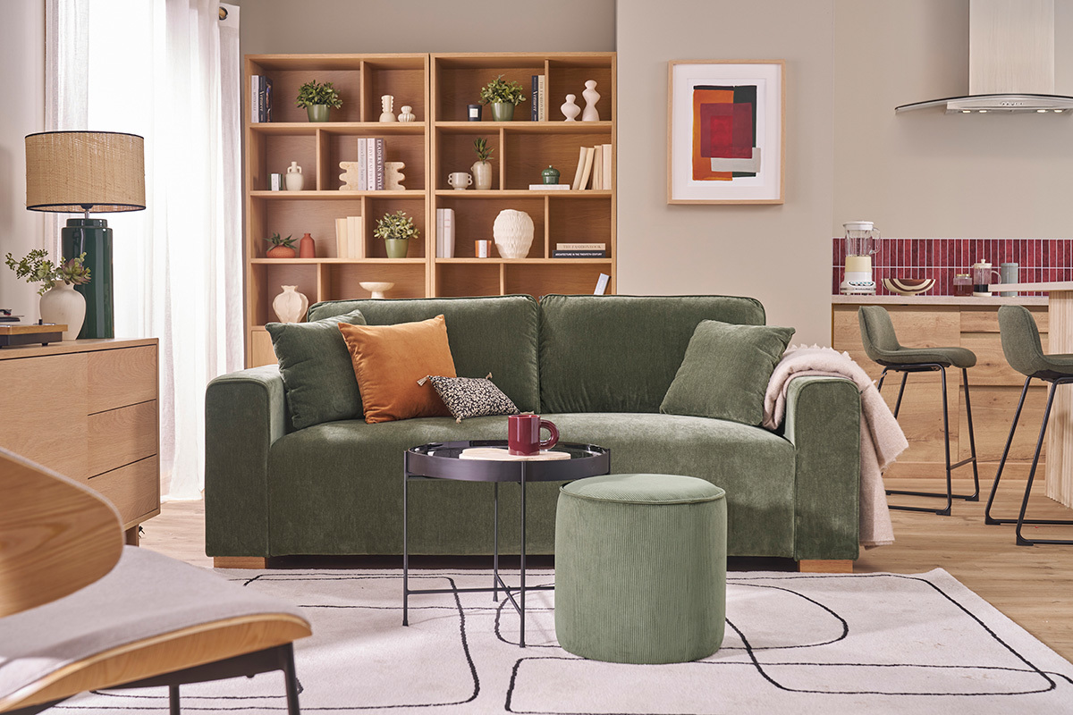 Canap� en tissu effet velours vert kaki, table basse ronde et pouf, dans salon moderne.