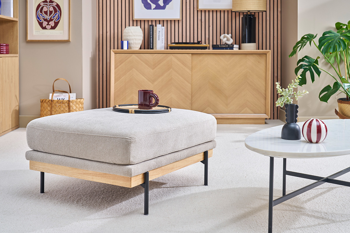 Repose-pieds en tissu chenille beige et mtal noir dans un salon lgant.