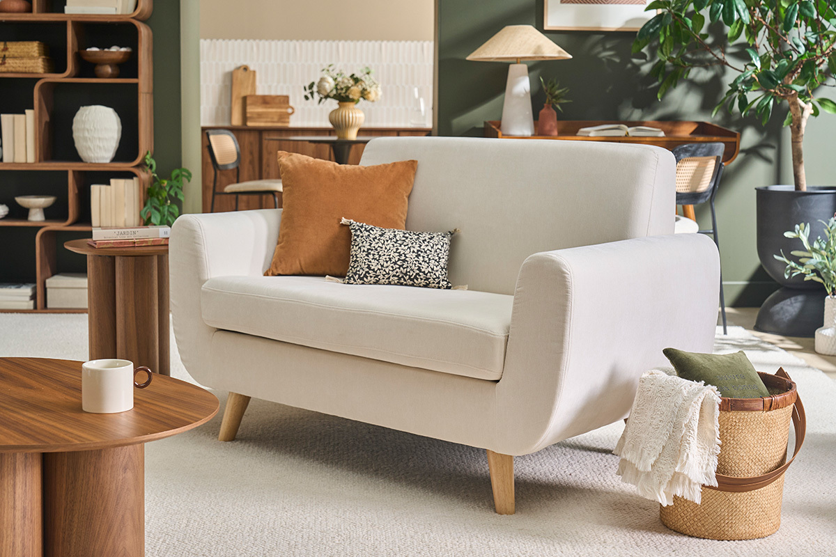 Canap� scandinave 2 places en tissu beige, bois clair, angle de c�t�, dans un salon d�cor�.
