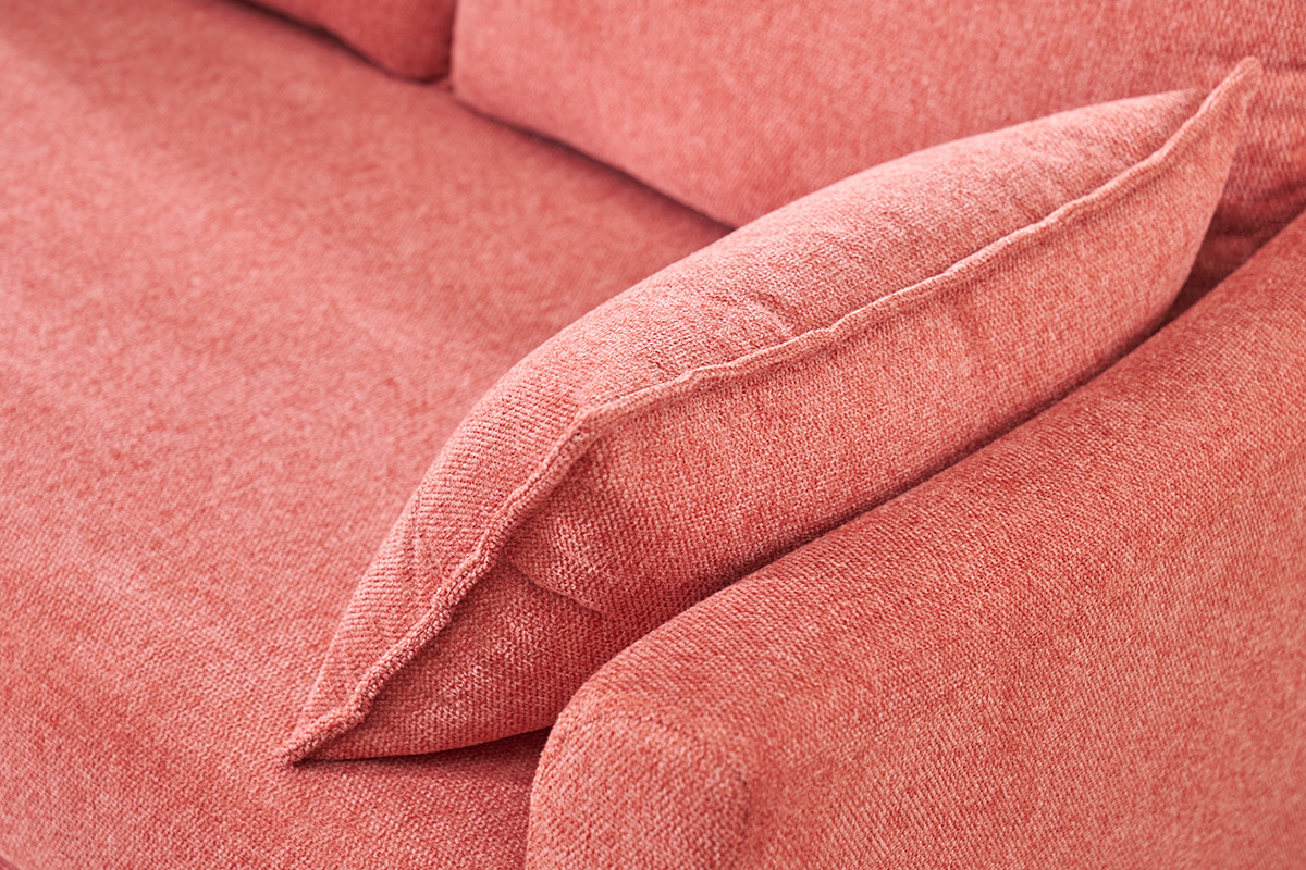 Gros plan sur accoudoir et coussin d'un canap� en tissu effet velours terracotta.