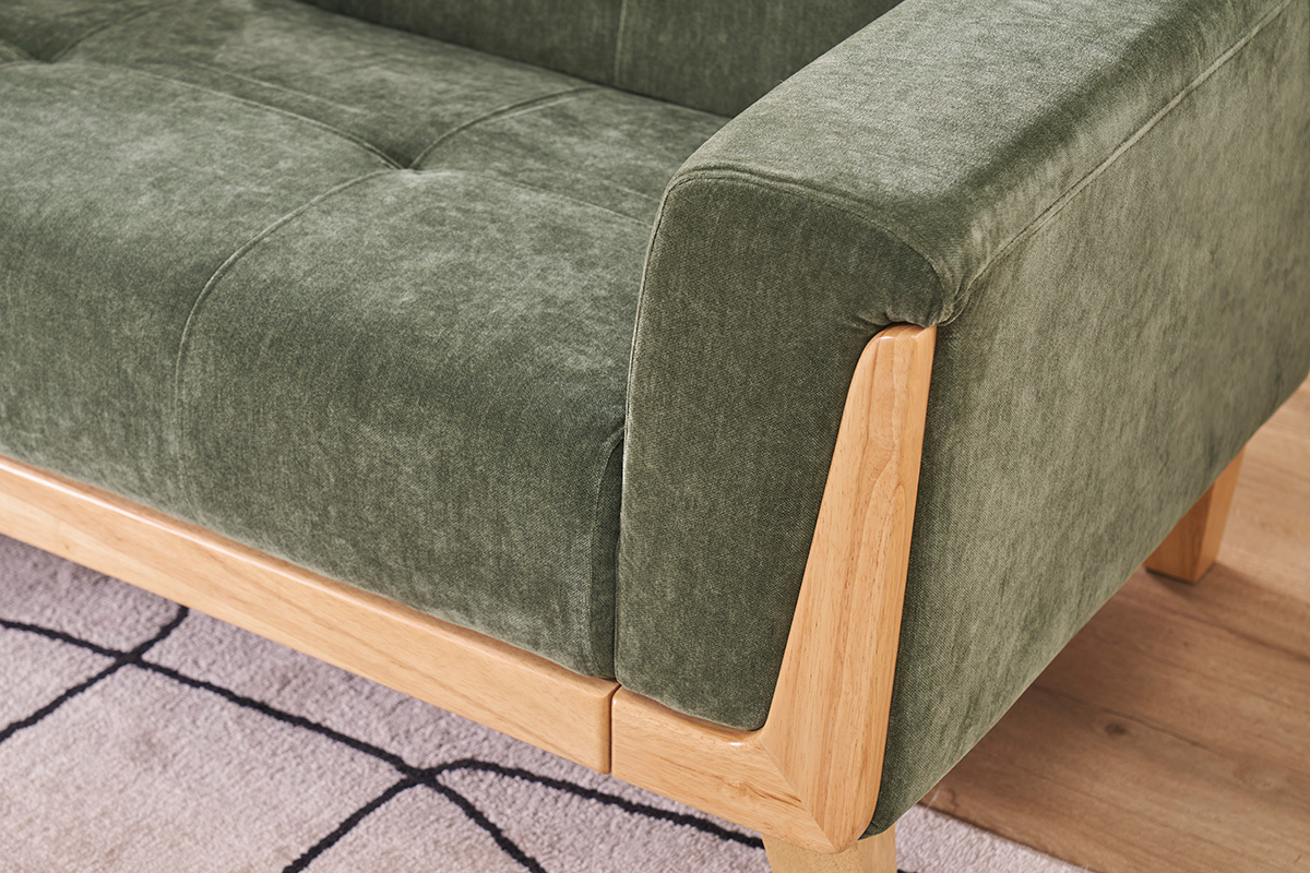 D�tail d'un canap� scandinave vert kaki en tissu effet velours avec accoudoir en bois clair.