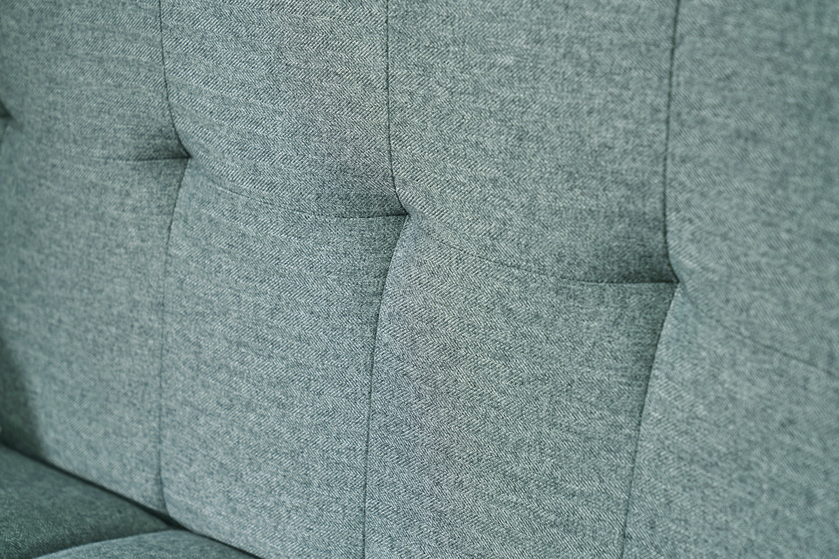 Gros plan sur le dossier capitonn� du canap� en tissu vert de gris.