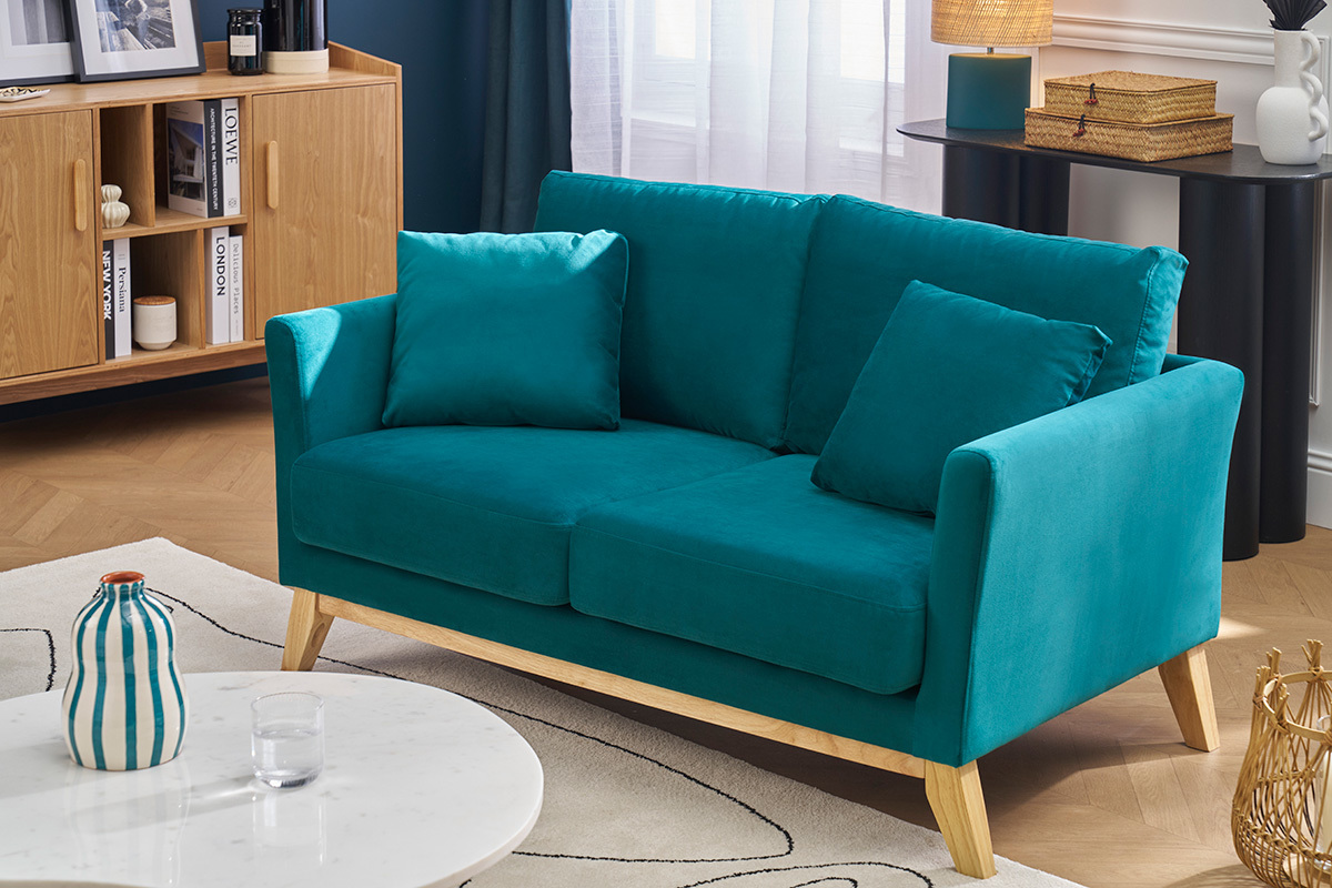 Canap scandinave 2 places en velours bleu ptrole et bois clair dans un salon moderne.