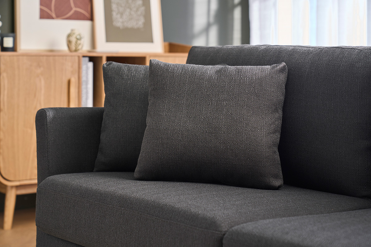 Canap� scandinave gris fonc� avec coussins, vue partielle, meuble en bois clair � l'arri�re-plan.