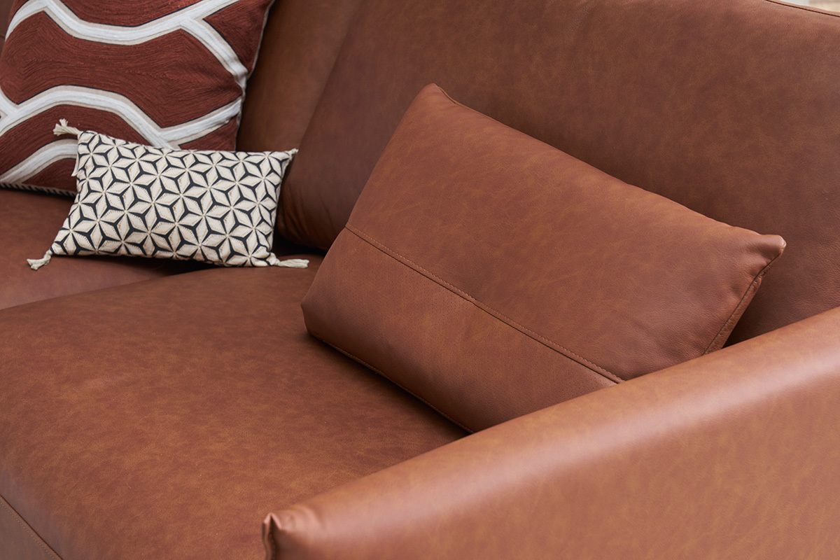 Vue rapproche d'un canap en cuir marron avec coussins dcoratifs.