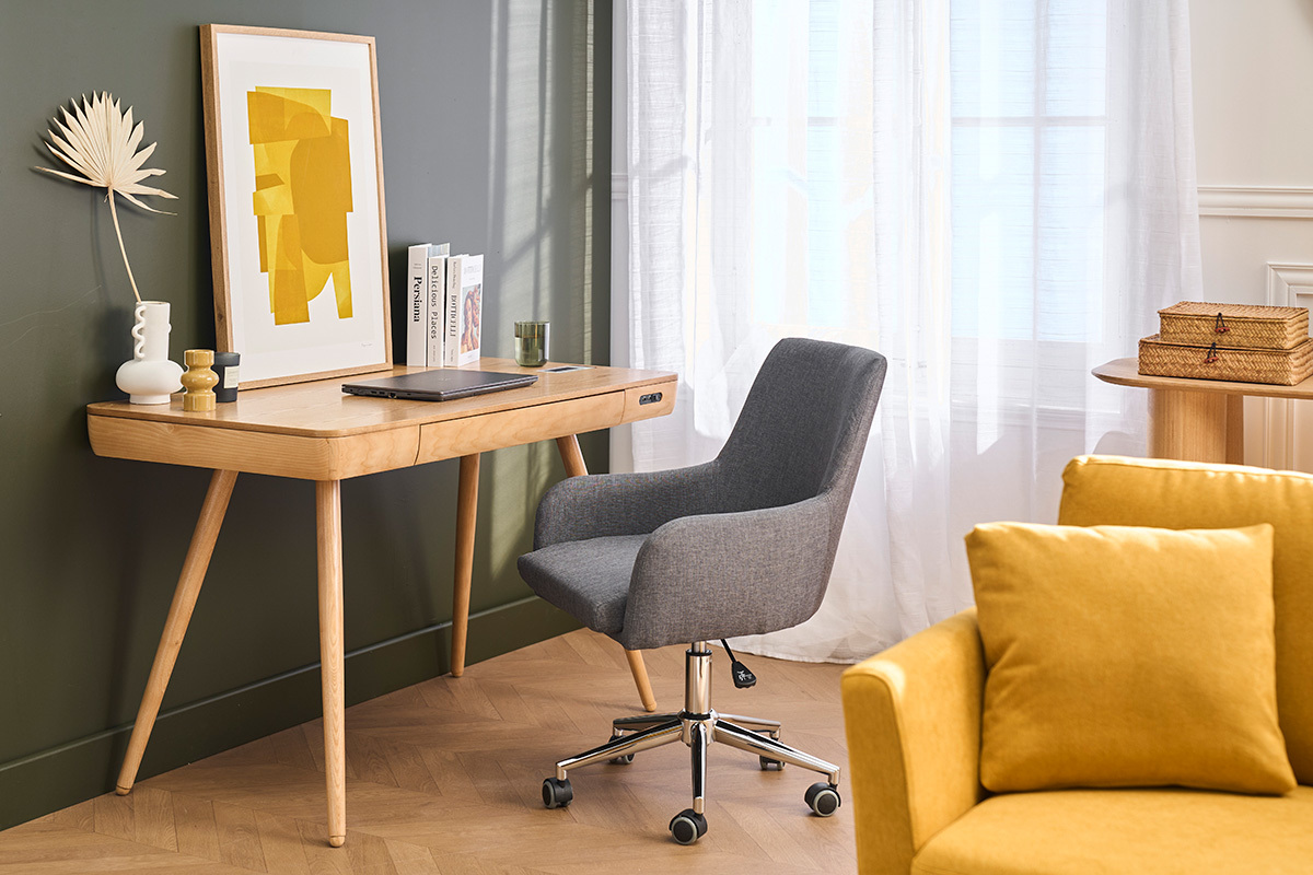 Chaise de bureau grise SHANA sur roulettes, devant un bureau en bois, vue d'angle.