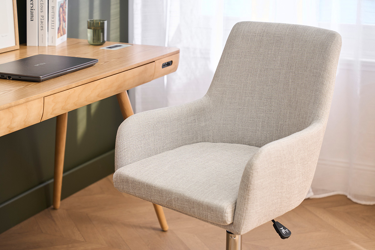 Chaise de bureau SHANA en tissu gris clair et acier, vue de c�t� devant un bureau en bois.