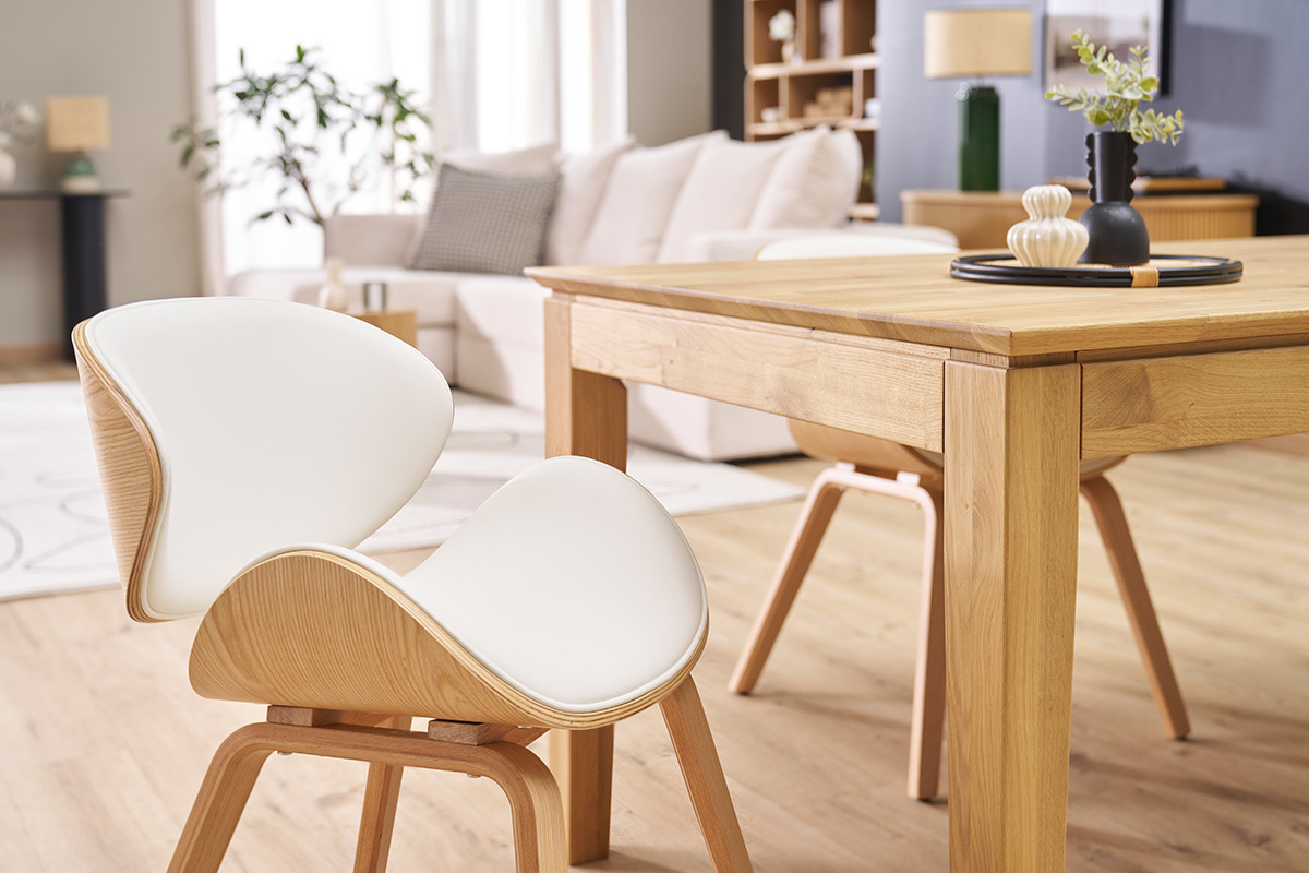 Chaise design blanc et bois clair WALNUT prs d'une table en bois, vue de profil dans un salon.