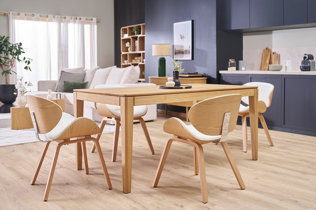 Chaises design blanc et bois clair autour d'une table en bois dans un salon lumineux.
