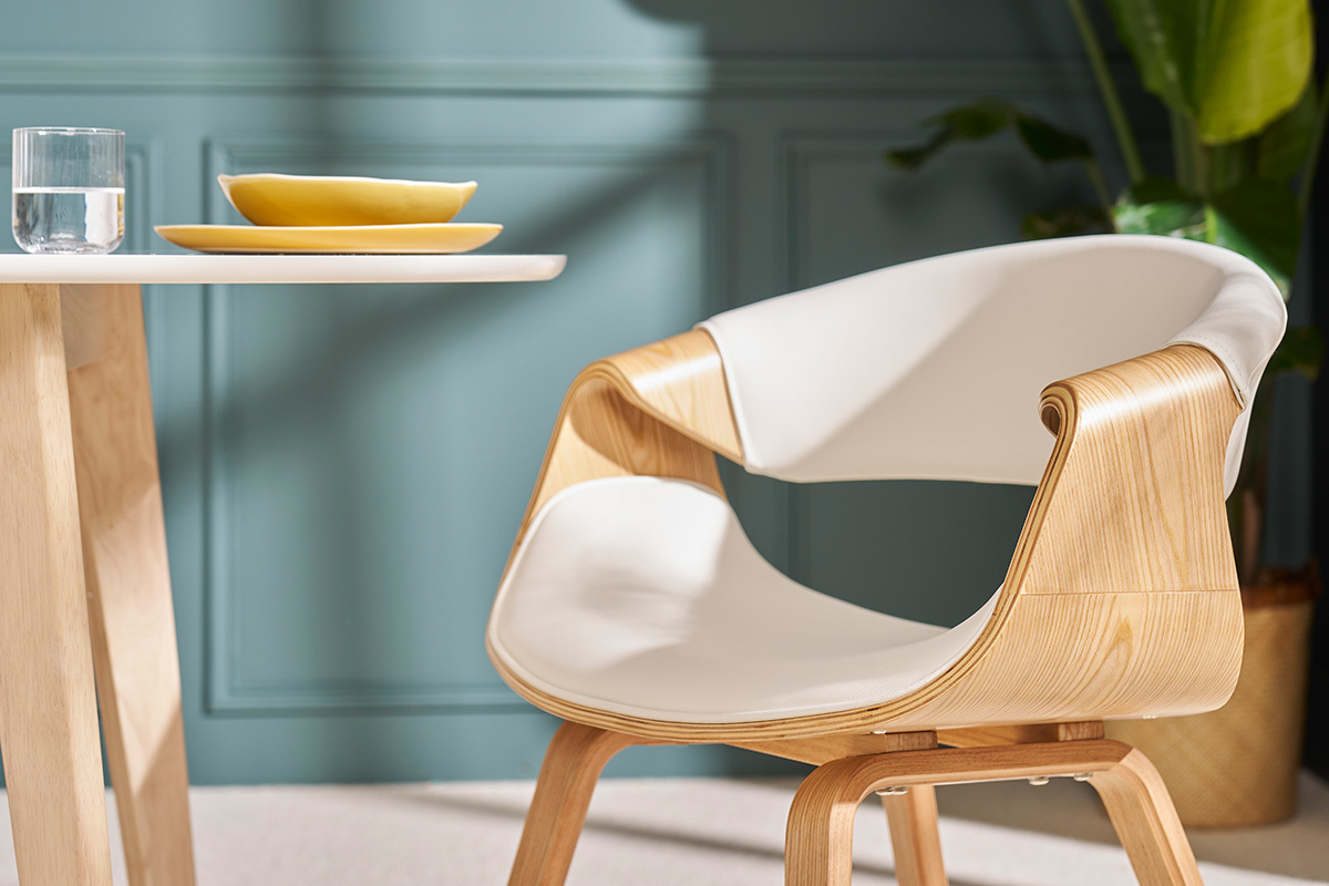 Chaise design ARAMIS blanche et bois clair, vue de profil, avec table et assiette en arri�re-plan.