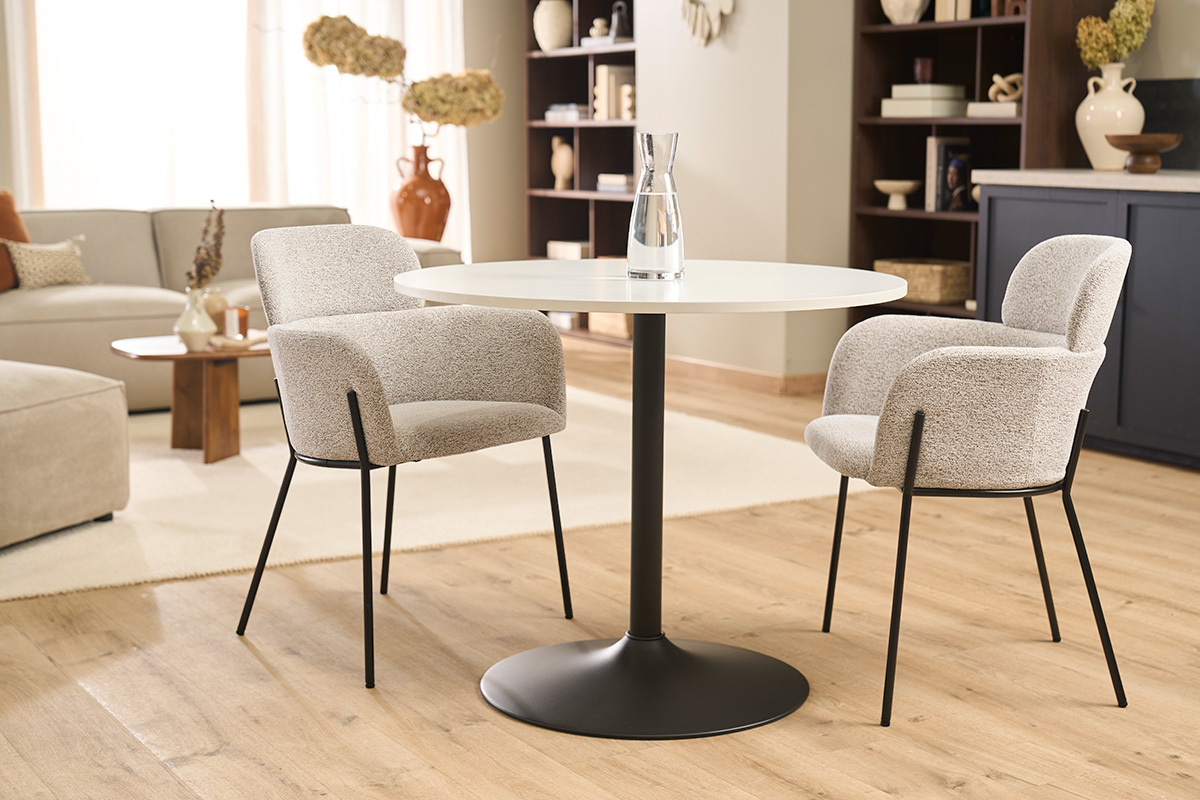 Deux chaises TULUM en velours beige autour d'une table ronde blanche dans un salon moderne.