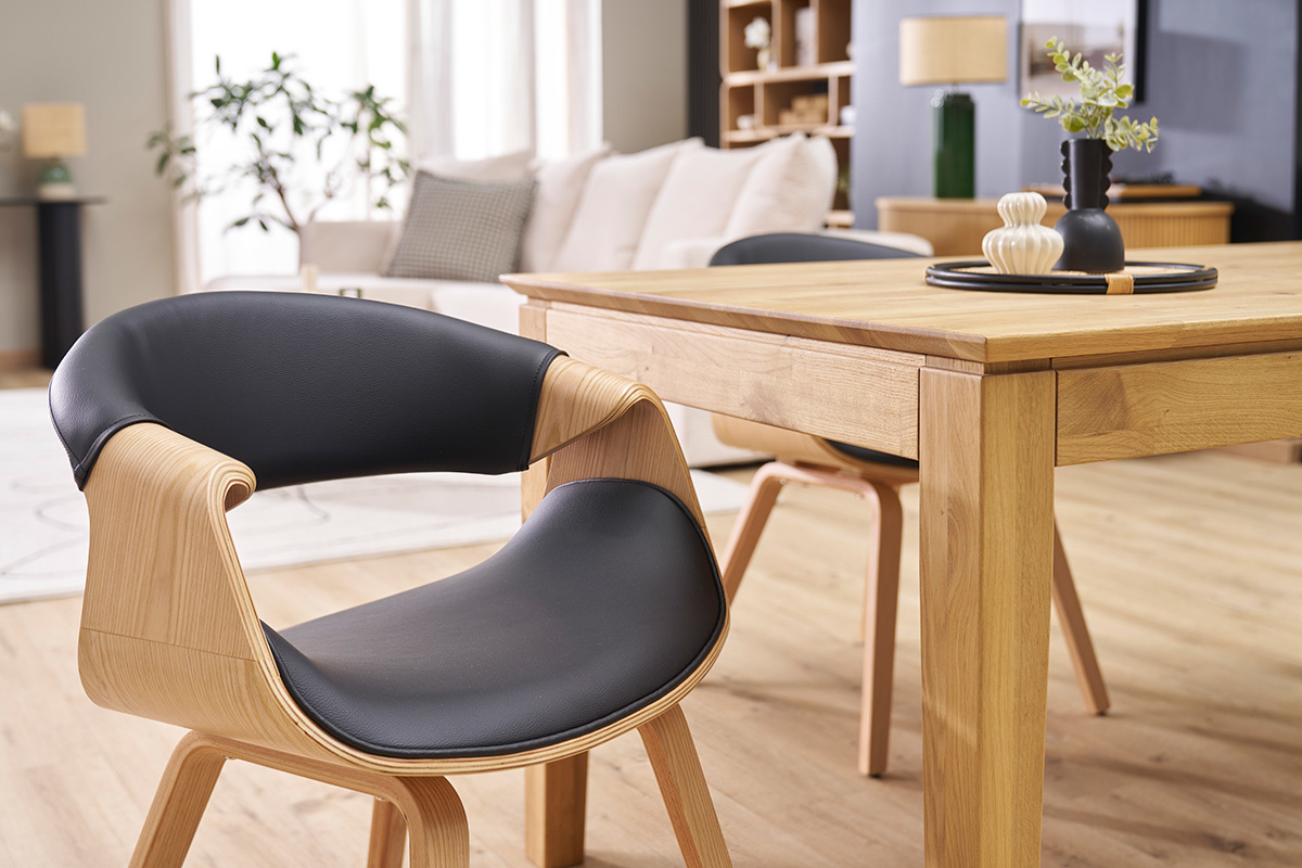 Chaise design ARAMIS en bois clair et cuir noir prs d'une table en bois, vue d'intrieur.
