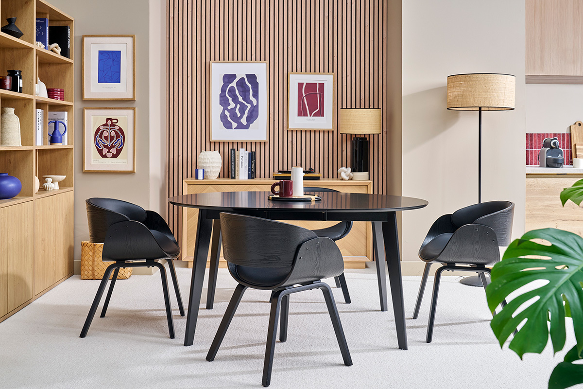 Chaises noires BENT autour d'une table noire dans un salon moderne avec des tagres et des cadres.