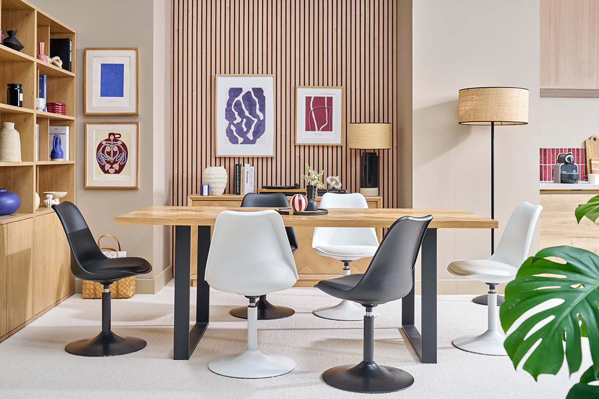Salle  manger avec chaises pivotantes blanches et noires autour d'une table en bois.