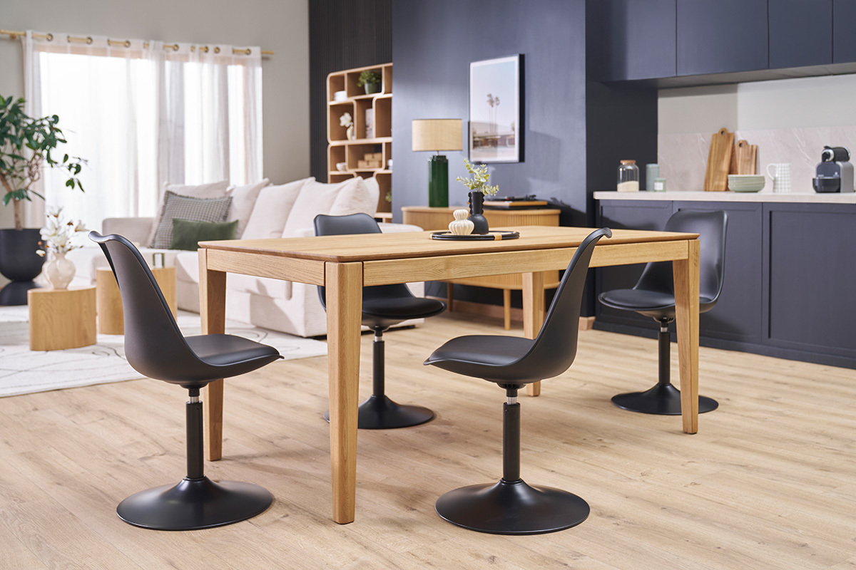 Trois chaises pivotantes noires STEEVY V2 autour d'une table en bois dans un salon moderne.