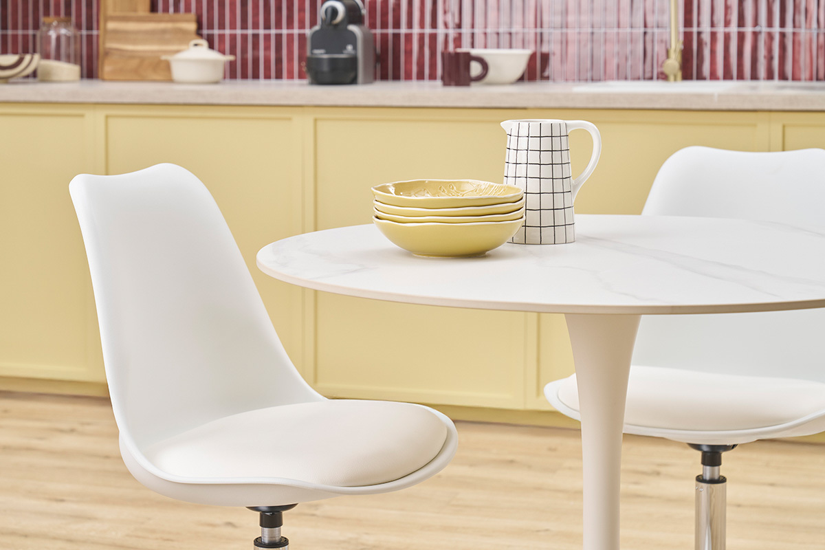 Chaise pivotante blanche STEEVY V2 prs d'une table, vue intrieure de cuisine.