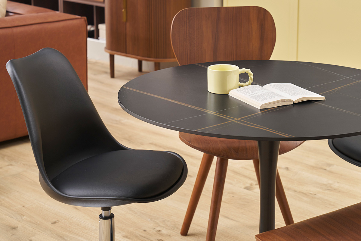 Chaise pivotante noire STEEVY V2 prs d'une table, vue partielle.