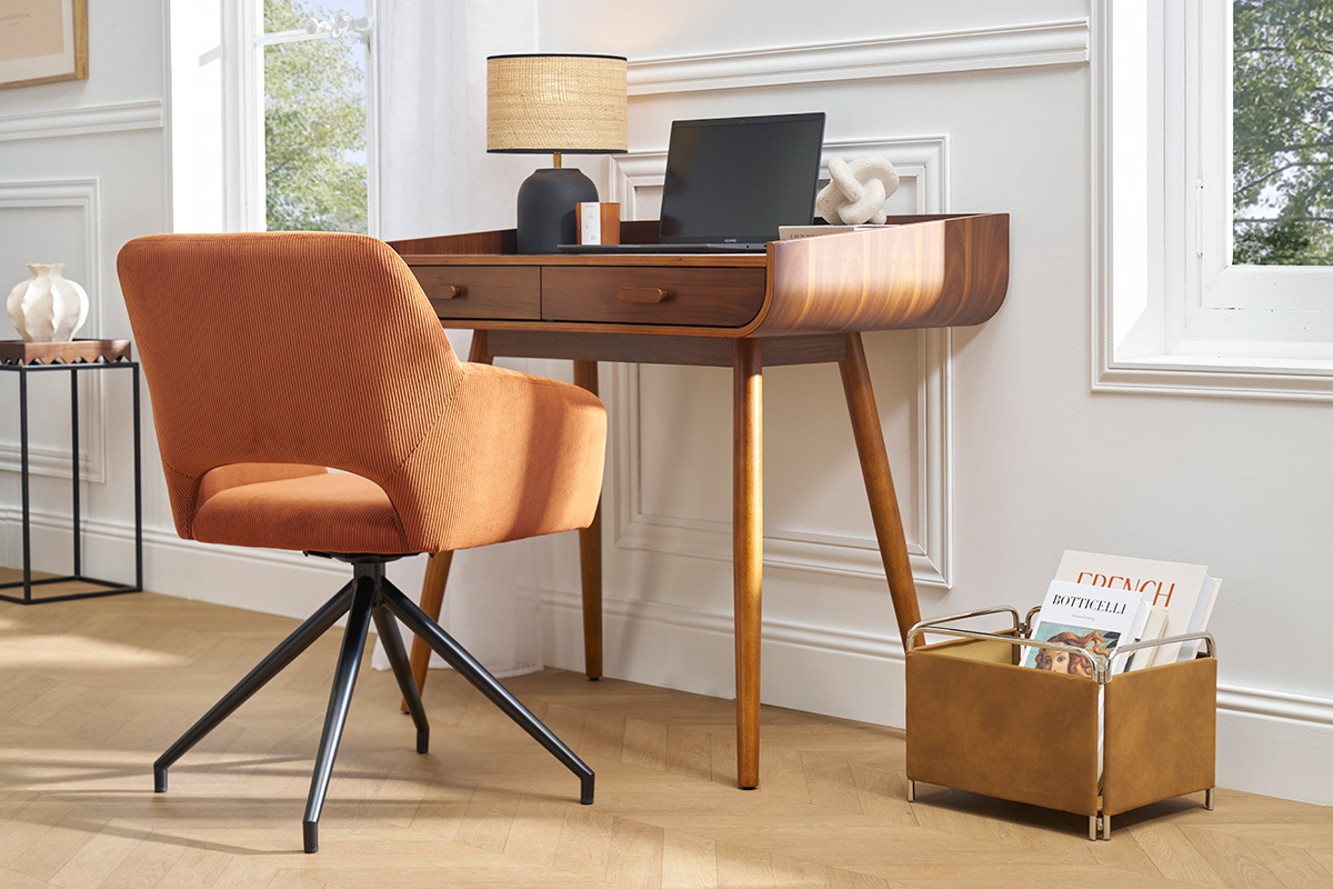 Chaise pivotante en velours ctel terre brle avec base en mtal noir, vue de ct prs d'un bureau en bois.