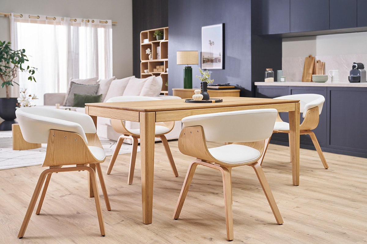 Salle  manger avec chaises scandinaves blanches et bois clair autour d'une table en bois.